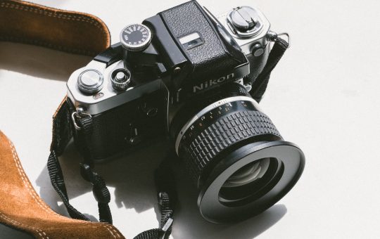 black Nikon DSLR camera on white surface